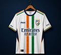 A white India national football team home jersey by PMX, featuring vertical orange, white, and green stripes down the center, with the Emirates Fly Better sponsor logo on the chest, displayed on a wooden hanger against a dark navy background.